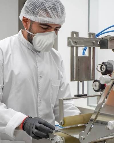 Operario del laboratorio operando la máquina selladora de envases
